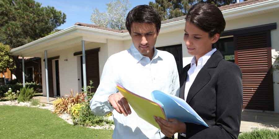 Become a successful realtor A realtor with a client in front of a hows