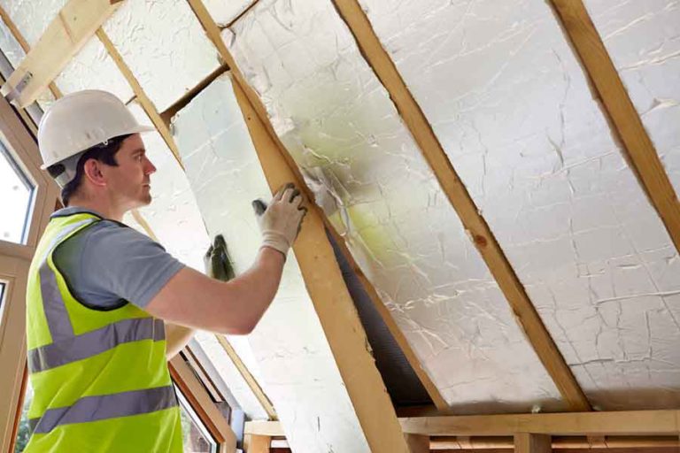 insulating-a-house How to Lower Heating Costs man installing insulation