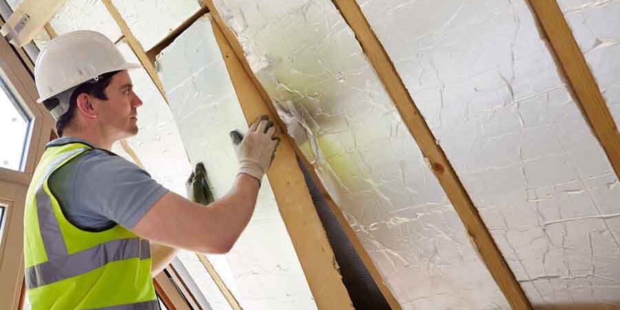 How to Lower Heating Costs man installing insulation
