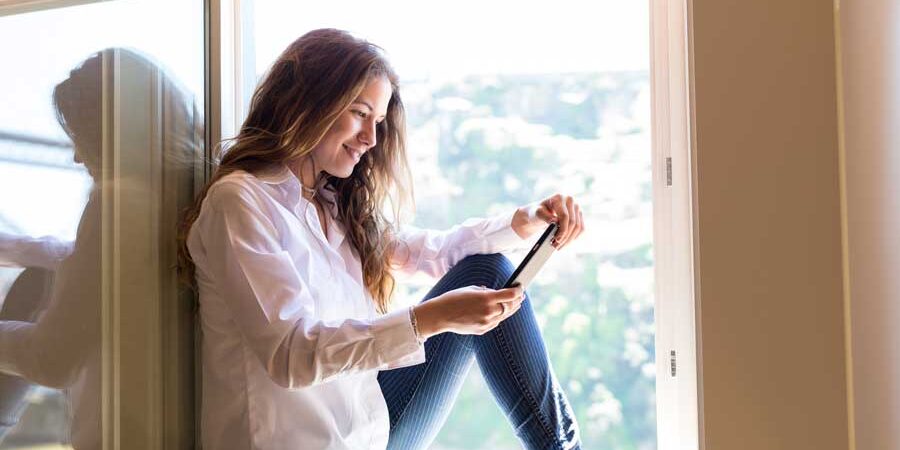 Young-woman-sitting-at-a-window-using-her-smart-phone Young-woman-sitting-at-a-window-using-her-smart-phone Typical of millennial homebuyers