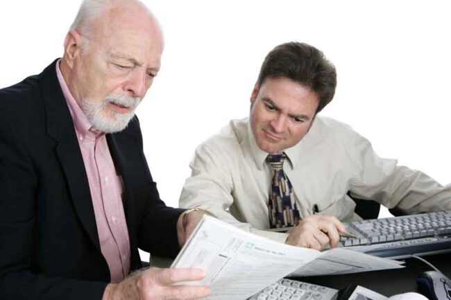 Property Taxes an elderly man seems holding tax forms sitting with an accountant