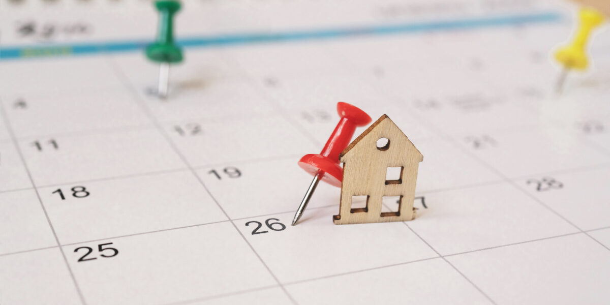red thumbtack with miniature wooden house on white calendar Homebuying timeline calendar
